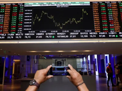 FILE PHOTO: A man takes a picture with his phone of an electronic board showing the recent fluctuations of market indices on Brazil's B3 Stock Exchange in Sao Paulo, Brazil October 28, 2021. REUTERS/Amanda Perobelli/File Photo