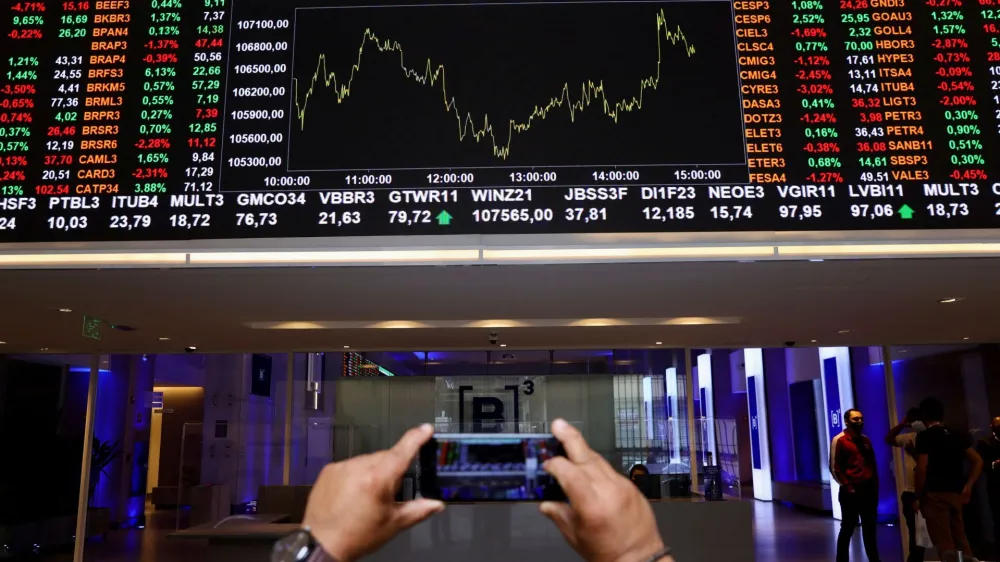 FILE PHOTO: A man takes a picture with his phone of an electronic board showing the recent fluctuations of market indices on Brazil's B3 Stock Exchange in Sao Paulo, Brazil October 28, 2021. REUTERS/Amanda Perobelli/File Photo