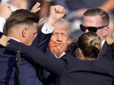 Republican presidential candidate former President Donald Trump is helped off the stage by U.S. Secret Service agents at a campaign event in Butler, Pa., on Saturday, July 13, 2024. (AP Photo/Gene J. Puskar)