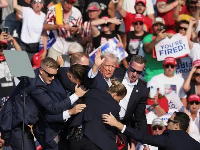 Republican presidential candidate and former U.S. President Donald Trump gestures with a bloodied face while he is assisted by U.S. Secret Service personnel after he was shot in the right ear during a campaign rally at the Butler Farm Show in Butler, Pennsylvania, U.S., July 13, 2024. REUTERS/Brendan McDermid