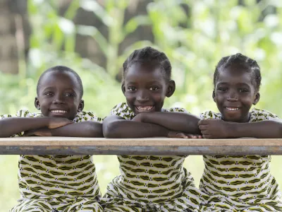 ﻿Three African children proudly sitting in their desk at school in Bamako, Mali. Candid outdoor shot of one boy and two girls learning their lessons at school.