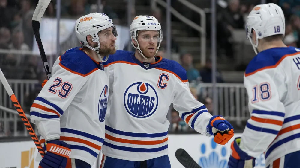 Edmonton Oilers center Connor McDavid, middle, celebrates with center Leon Draisaitl, left, and left wing Zach Hyman after scoring against the San Jose Sharks during the second period of an NHL hockey game in San Jose, Calif., Friday, Jan. 13, 2023. (AP Photo/Godofredo A. Vásquez)