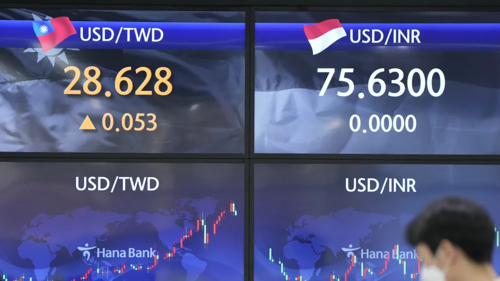 A currency trader stands near screens showing the foreign exchange rates at a foreign exchange dealing room in Seoul, South Korea, Wednesday, March 30, 2022. Asian stock markets followed Wall Street higher on Wednesday as talks on ending Russia's war on Ukraine appeared to make progress. (AP Photo/Lee Jin-man)