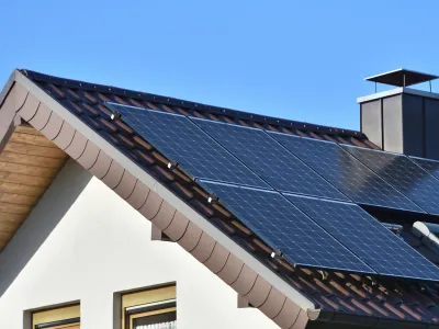 Solar panels installed on the roof of a house with tiles in Europe against the background of a blue sky. Green technology