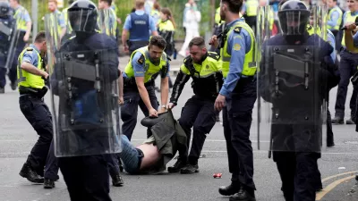 15 July 2024, Ireland, Dublin: Irish Gardai officers detain a protesters after a number of fires have been started at the former site of the Crown Paints factory in Coolock. Photo: Niall Carson/PA Wire/dpa