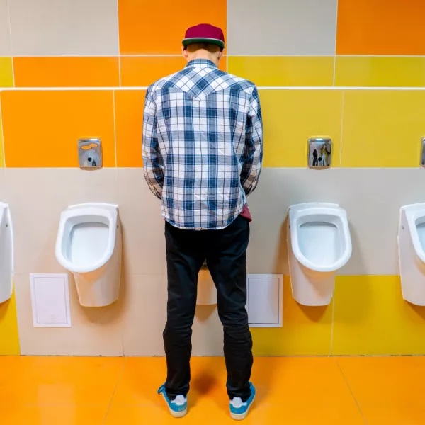 young man in the public toilet, standing next to the urinal in the trade center / Foto: Михаил Руденко