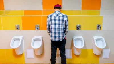 young man in the public toilet, standing next to the urinal in the trade center / Foto: Михаил Руденко