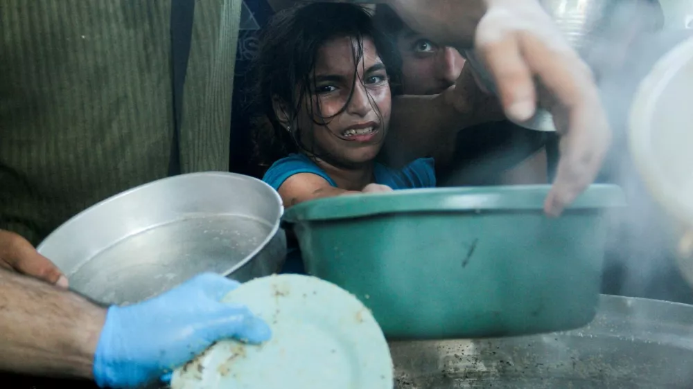 Palestinian children gather to receive food cooked by a charity kitchen, amid food scarcity, as Israel-Hamas conflict continues, in the northern Gaza Strip, July 18, 2024. REUTERS/Mahmoud Issa   TPX IMAGES OF THE DAY