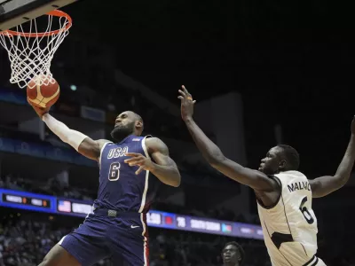 United States' forward LeBron James scores as South Sudan's center Khaman Maluach attempted top defend during an exhibition basketball game between the United States and South Sudan, at the o2 Arena in London, Saturday, July 20, 2024. (AP Photo/Kin Cheung)