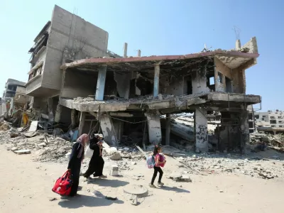 A Palestinian woman holds a child as they flee the eastern part of Khan Younis to make their way after they were ordered by Israeli army to evacuate their neighborhoods, amid Israel-Hamas conflict, in Khan Younis in the southern Gaza Strip July 22, 2024. REUTERS/Hatem Khaled