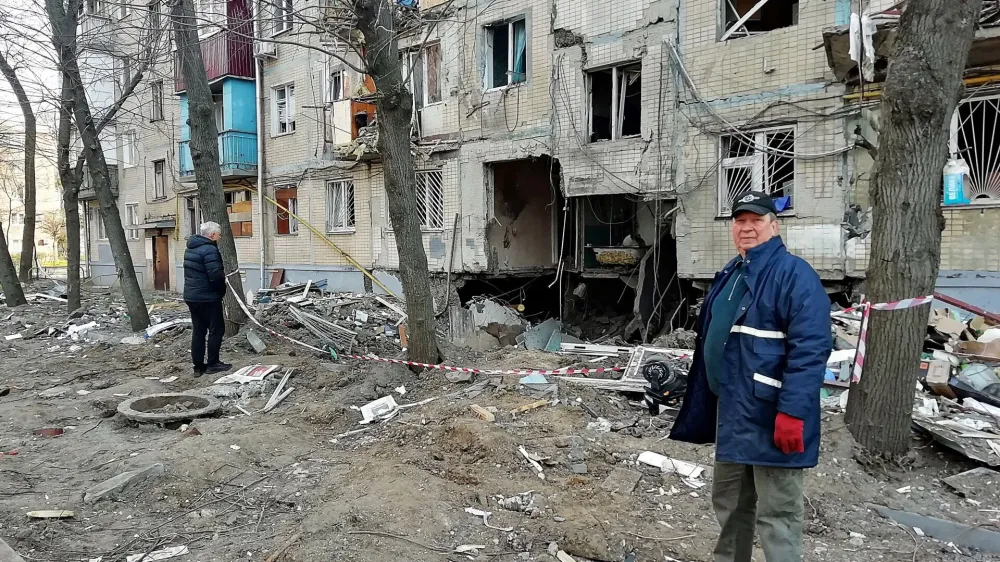 A man looks on as he stands next to a residential building hit in a military strike, amid Russia's invasion, in Kharkiv, Ukraine, April 10, 2022. REUTERS/Oleksandr Lapshyn