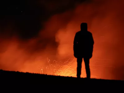 A person looks on as smoke and lava rise from a crater of Mount Etna, Europe's most active volcano in Italy July 23, 2024. REUTERS/Etna Walk/Marco Restivo   TPX IMAGES OF THE DAY