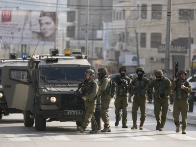 Israeli soldiers take up positions at the scene of a Palestinian shooting attack on an Israeli car at the Hawara checkpoint, near the West Bank city of Nablus, Sunday, Feb. 26, 2023. Two Israelis were killed in the shooting, Israeli officials said. (AP Photo/Majdi Mohammed)