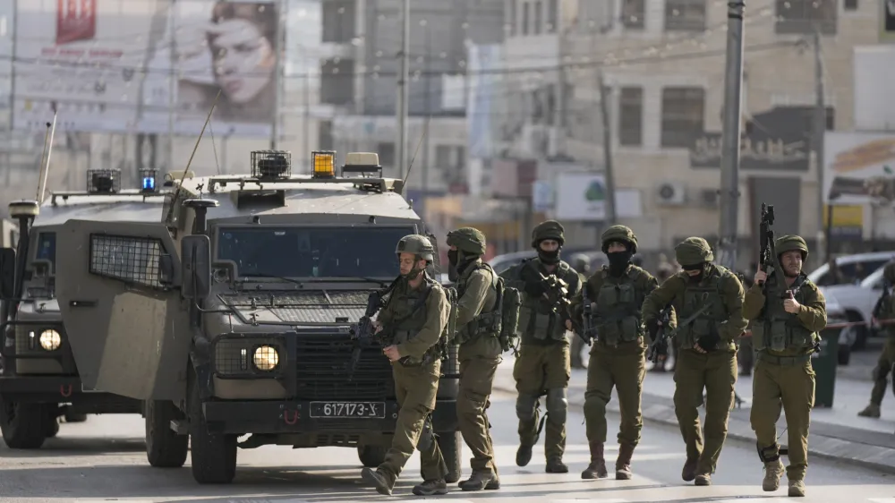 Israeli soldiers take up positions at the scene of a Palestinian shooting attack on an Israeli car at the Hawara checkpoint, near the West Bank city of Nablus, Sunday, Feb. 26, 2023. Two Israelis were killed in the shooting, Israeli officials said. (AP Photo/Majdi Mohammed)