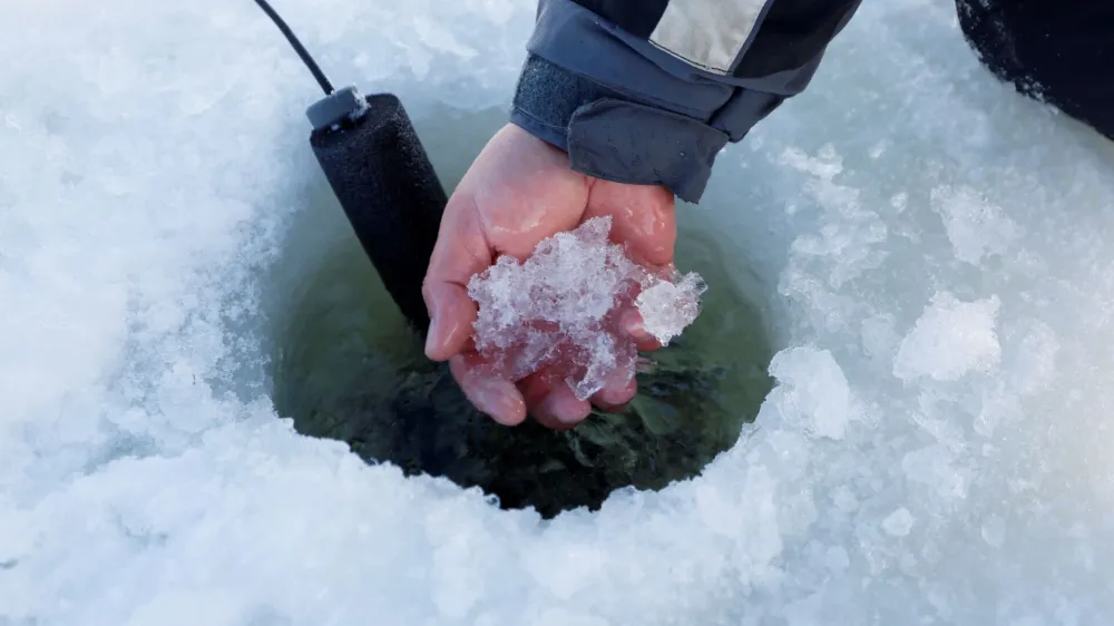 Indigenous fisherman Mike Diabo scoops shush out of a freshly drilled ice fishing hole on a lake in the Kitigan Zibi Anishinabeg Reserve, Quebec, Canada, February 22, 2023. First Nations ice fishermen risk going out on ice as climate change affects the quality of the ice. REUTERS/Blair Gable