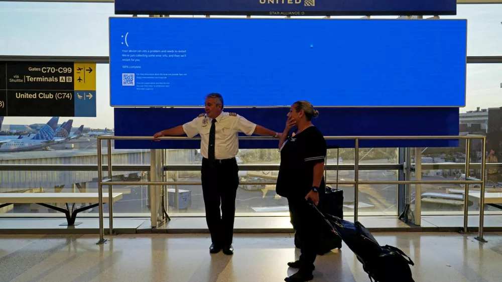 United Airlines employees wait by a departures monitor displaying a blue error screen, also known as the "Blue Screen of Death" inside Terminal C in Newark International Airport, after United Airlines and other airlines grounded flights due to a worldwide tech outage caused by an update to CrowdStrike's "Falcon Sensor" software which crashed Microsoft Windows systems, in Newark, New Jersey, U.S., July 19, 2024. REUTERS/Bing Guan   TPX IMAGES OF THE DAY