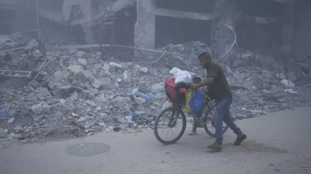 Palestinians walk through dust by the rubble of houses, destroyed by Israeli strikes in Khan Younis, Gaza Strip, Monday, July 22, 2024. (AP Photo/Abdel Kareem Hana)