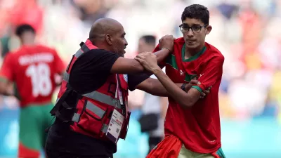 Paris 2024 Olympics - Football - Men's Group B - Argentina vs Morocco - Geoffroy-Guichard Stadium, Saint-Etienne, France - July 24, 2024. Pitch invader is detained by a steward after the match. REUTERS/Thaier Al-Sudani