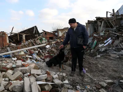 Local resident Volodymyr Alipov, 58, pets a dog among remains of his house destroyed last year by an airstrike during Russia's attack in the village of Tsyrkuny, Kharkiv region, Ukraine March 20, 2023. REUTERS/Sofiia Gatilova