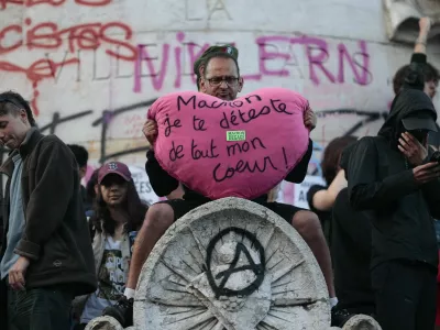 A protester holds a big plush heart with the slogan "Macron, I hate you with all my heart" as people gather at the Place de la Republique after partial results in the second round of the early French parliamentary elections, in Paris, France, July 7, 2024. REUTERS/Abdul Saboor