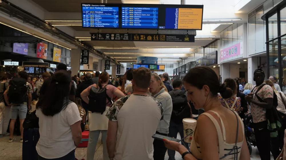 Travelers check trains on an electronic board at the Gare de Montparnasse, at the 2024 Summer Olympics, Friday, July 26, 2024, in Paris, France. Hours away from the grand opening ceremony of the Olympics, high-speed rail traffic to the French capital was severely disrupted on Friday following what officials described as "criminal actions" and sabotage. (AP Photo/Yasin Dar)