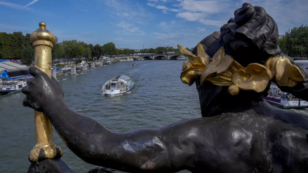 A tourist boat makes its way along the Seine River by the Alexandre III bridge, at the 2024 Summer Olympics, Sunday, July 28, 2024, in Paris, France. (AP Photo/Yasin Dar)