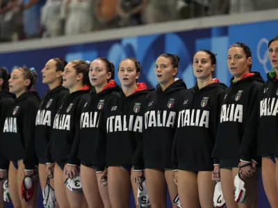 Players from Italy listen to their national anthem prior to a women's water polo group B preliminary match between Italy and USA, at the 2024 Summer Olympics, Wednesday, July 31, 2024, in Saint-Denis, France. (AP Photo/Luca Bruno)