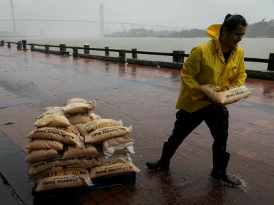 A worker moves sandbags in the rain at River Street as Tropical Storm Debby moves towards Georgia, in Savannah, Georgia, U.S., August 5, 2024. REUTERS/Marco Bello