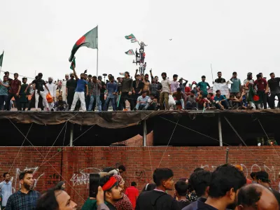 People waves Bangladeshi flags on top of the Ganabhaban, the Prime Minister's residence, as they celebrate the resignation of PM Sheikh Hasina in Dhaka, Bangladesh, August 5, 2024. REUTERS/Mohammad Ponir Hossain