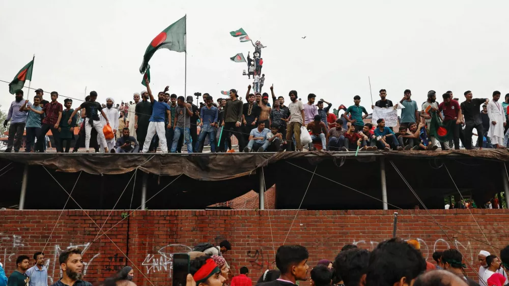 People waves Bangladeshi flags on top of the Ganabhaban, the Prime Minister's residence, as they celebrate the resignation of PM Sheikh Hasina in Dhaka, Bangladesh, August 5, 2024. REUTERS/Mohammad Ponir Hossain