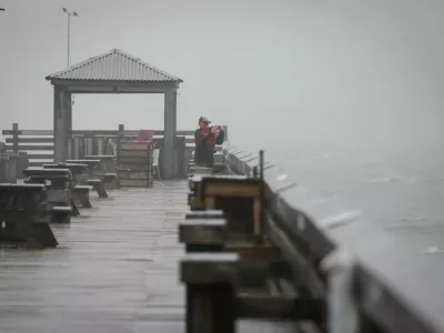 A woman uses her phone to capture images from the pier as Tropical Storm Debby drifts in the East Coast, in Myrtle Beach, South Carolina, U.S., August 7, 2024. REUTERS/Marco Bello