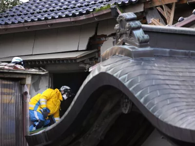 Police officers go into a building at the premises of a temple to search for victims in Wajima in the Noto peninsula, facing the Sea of Japan, northwest of Tokyo, Saturday, Jan. 6, 2024, following Monday's deadly earthquake. (AP Photo/Hiro Komae)