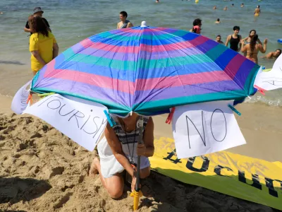 11 August 2024, Spain, El Arenal: "Tourism - No" is written on two pieces of paper on a parasol on a beach in Mallorca in protest against mass tourism on the Balearic island. Photo: Clara Margais/dpa / Foto: Clara Margais