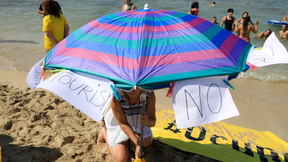 11 August 2024, Spain, El Arenal: "Tourism - No" is written on two pieces of paper on a parasol on a beach in Mallorca in protest against mass tourism on the Balearic island. Photo: Clara Margais/dpa / Foto: Clara Margais