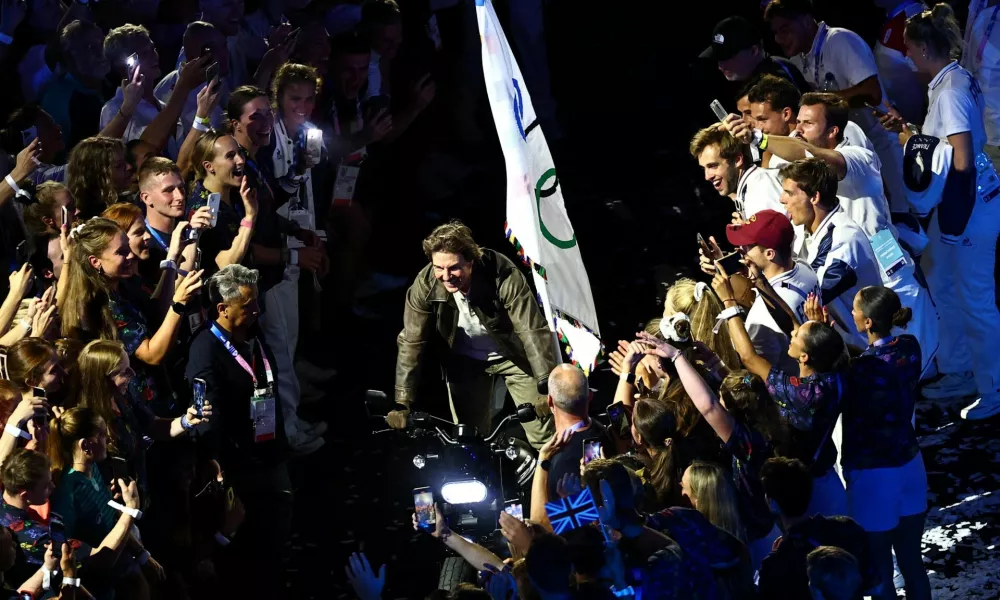 Paris 2024 Olympics - Ceremonies - Paris 2024 Closing Ceremony - Stade de France, Saint-Denis, France - August 11, 2024. Actor Tom Cruise rides a motorbike with the Olympics flag among athletes during the closing ceremony. REUTERS/Tingshu Wang   TPX IMAGES OF THE DAY