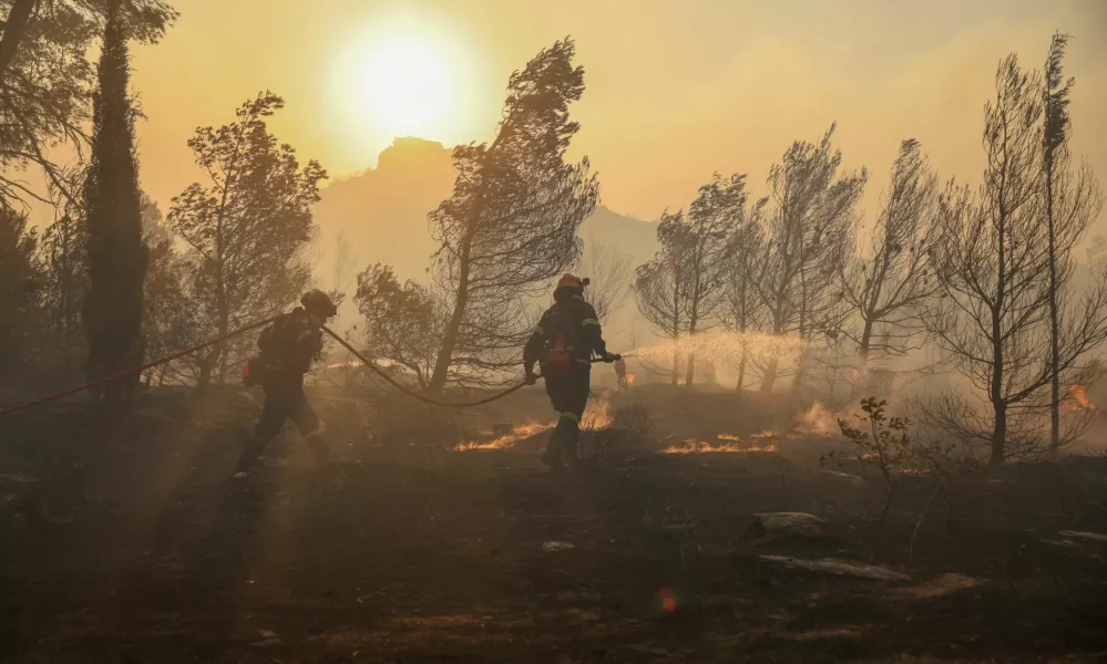 Firefighters try to extinguish a wildfire burning in Penteli, Greece, August 12, 2024. REUTERS/Stelios Misinas