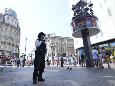 A Police officer stands at the scene in Leicester Square, as a man was arrested with the accusation of stabbing an 11-year-old girl and 34-year-old woman, in London, Monday Aug. 12, 2024. (James Manning/PA via AP)