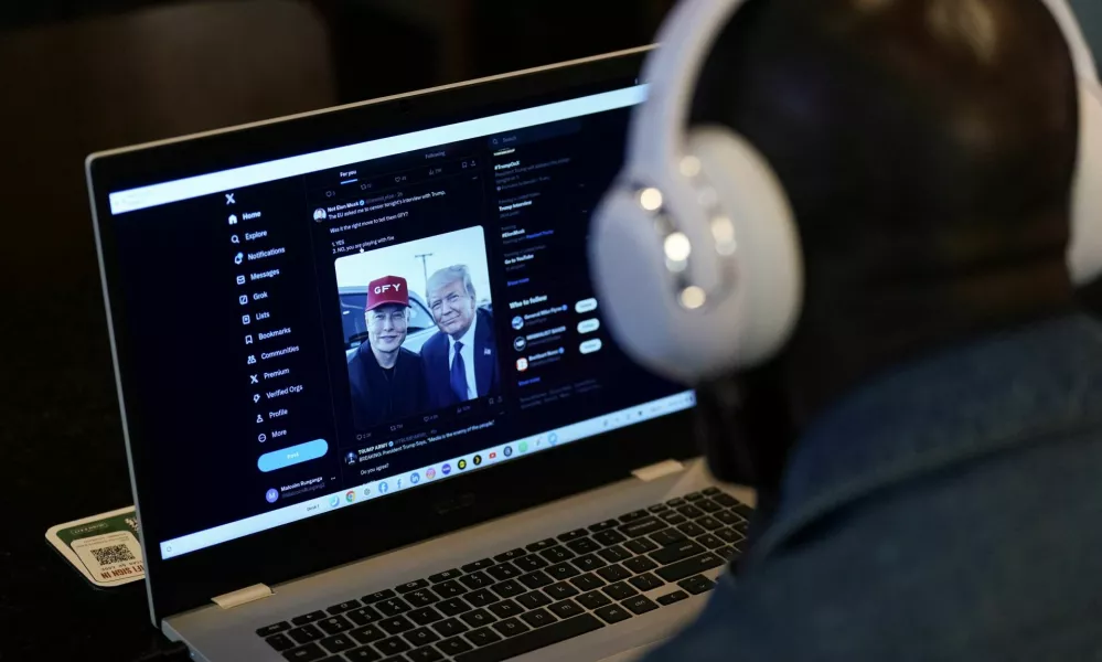 A person tries to watch on a laptop billionaire entrepreneur Elon Musk's interview with Republican presidential candidate and former U.S. President Donald Trump on the X social media network, in New York City, U.S. August 12, 2024. REUTERS/Adam Gray