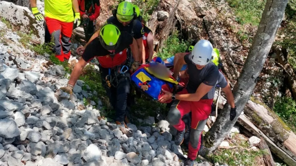 Med transportom pokojnika po strmem in zahtevnem gozdnem terenu je na enega od reševalcev padla skala in ga hudo poškodovala. Foto: GRS Kamnik