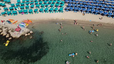 A drone view shows people swimming in the sea and umbrellas on a beach in Santa Marinella, north of Rome, Italy, August 13, 2024 REUTERS/Guglielmo Mangiapane