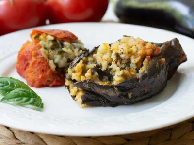 Traditional azerbaijani eggplant dolma also called three sisters made vegan: an aubergine and a tomato stuffed with spicy rice and basil instead of the minced beef in a white plate / Foto: Mehriban Aliyeva