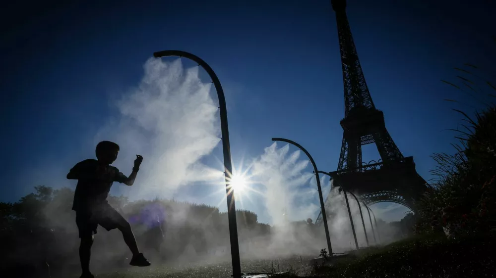 A boy plays under a spray of cooling water on a hot day outside the Eiffel Tower Stadium during the 2024 Olympics in Paris, France, July 28, 2024. REUTERS/Esa Alexander   "OLYMPIC BEHIND THE SCENES" FOR THIS STORY. SEARCH "OLYMPIC SIDELINES" FOR ALL STORIES.