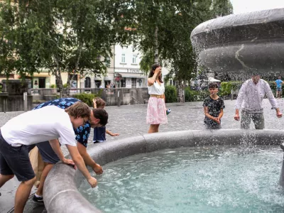 - Mimoidoči v Ljubljani se skušajo ohladiti v vodnjaku na Novem trgu.- 10.07.2024. - Vročinski val je zajelSlovenijo s temperaturima preko 30 stopinj.//FOTO: Bojan Velikonja