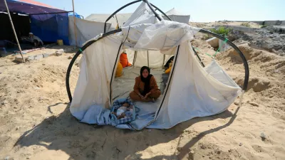 A displaced Palestinian woman and a child shelter in a cemetery, as Gaza health ministry announced that death toll has surpassed 40,000, amid the Israel-Hamas conflict, in Khan Younis, in the southern Gaza Strip, August 15, 2024. REUTERS/Hatem Khaled   TPX IMAGES OF THE DAY