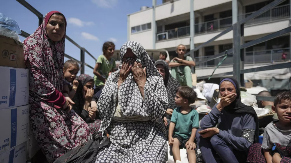 Palestinian women weep on a truck as she evacuates a school that had been her shelter, in eastern Deir al-Balah, Gaza Strip, Friday, Aug. 16, 2024, after the Israeli military dropped leaflets asking civilians to evacuate from the area, saying forces plan to respond to rocket fire that targeted Israel. (AP Photo/Abdel Kareem Hana)