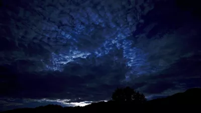 Clouds are lit by moon light as it rises behinds the Carnic Alps in the town of Obertilliach, in the Austrian region of east Tyrol, Sunday, Aug. 18, 2024. (AP Photo/Andrew Medichini)