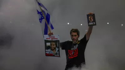 A man holds an Israeli national flag, and pictures of a hostage and Israeli Prime Minister Benjamin Netanyahu, as people demonstrate against Netanyahu's government and call for the release of hostages in Gaza, amid the Israel-Hamas conflict, in Tel Aviv, Israel, August 17, 2024. Picture taken with long exposure. REUTERS/Florion Goga