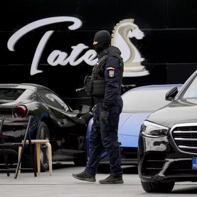 A masked gendarme patrols the courtyard of the residence of social media personality Andrew Tate during an early morning police search raid, on the outskirts of Bucharest, Romania, Wednesday, Aug. 21 2024. (AP Photo/ Vadim Ghirda)