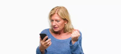 Middle age blonde woman sending message using smartphone over isolated background annoyed and frustrated shouting with anger, crazy and yelling with raised hand, anger concept / Foto: Aaronamat