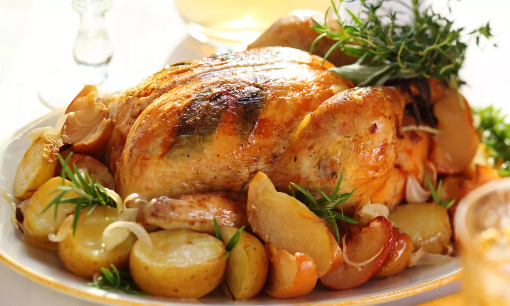 Whole roasted chicken with potatoes and apples on white plate / Foto: Elenagaak